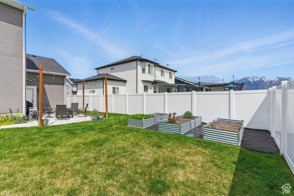 View of yard featuring a mountain view, a garden, fence private yard, and a patio