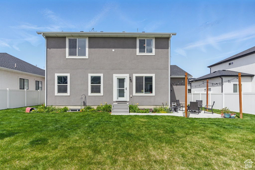 Back of property with a yard, fence, and stucco siding