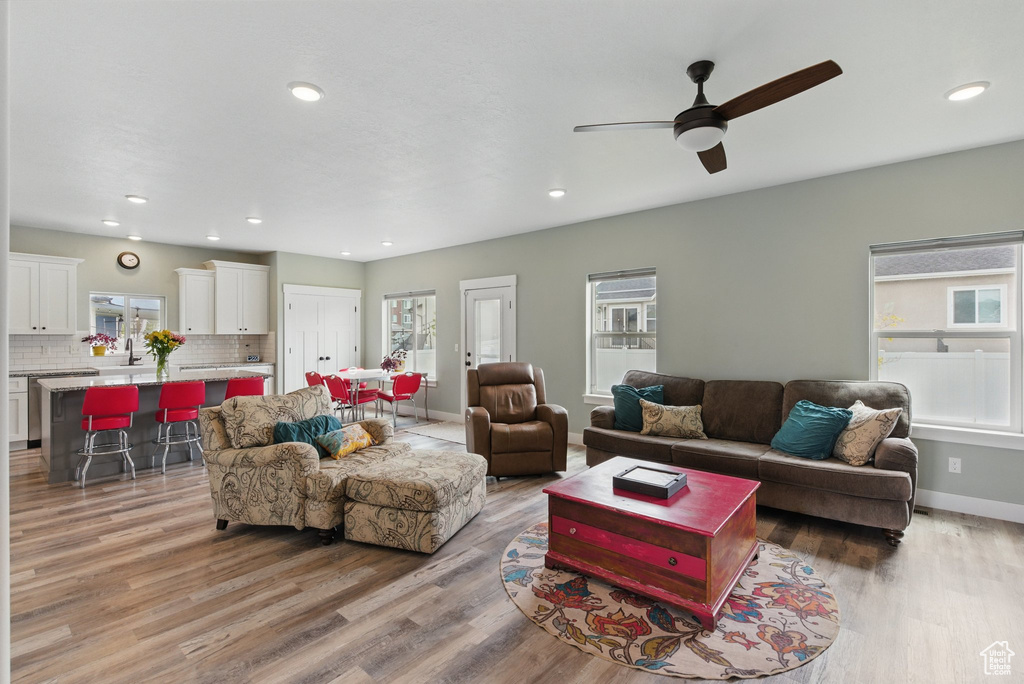 Living room with light wood-style floors, recessed lighting, baseboards, and ceiling fan