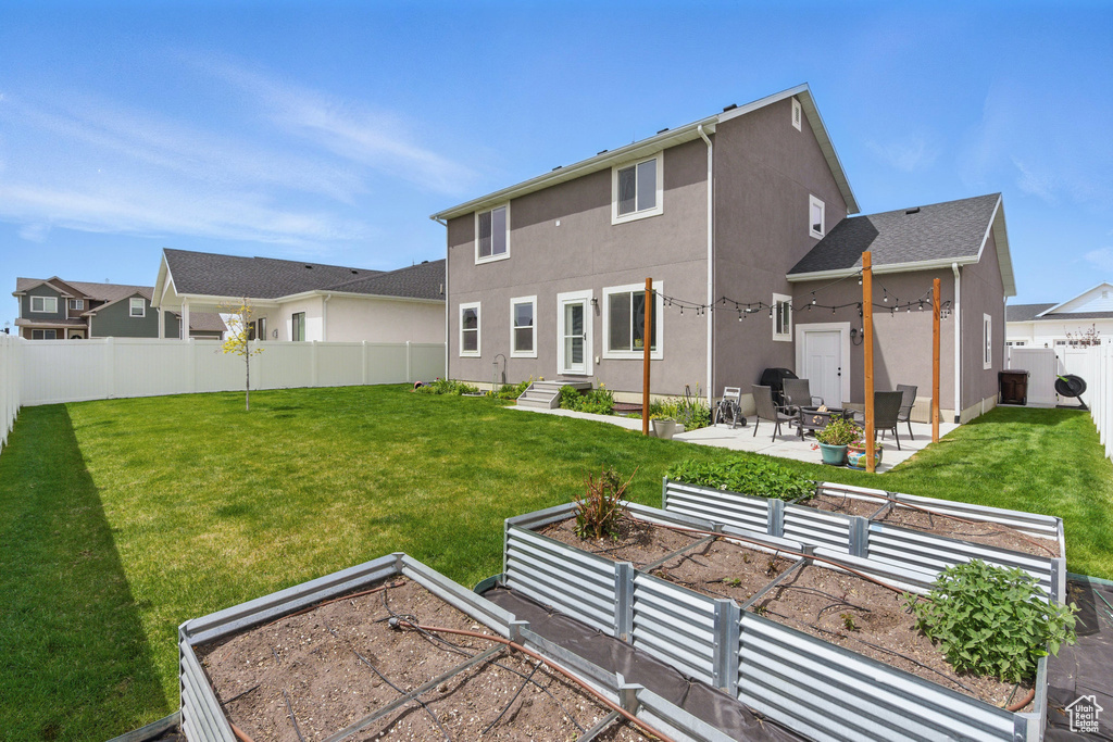 Back of house with a garden, a patio, a fenced backyard, stucco siding, and a yard