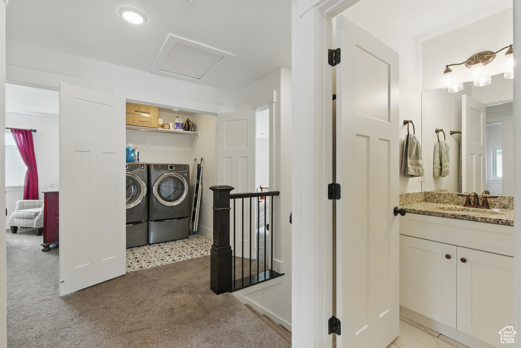 Washroom with laundry area, attic access, washing machine and clothes dryer, a sink, and light carpet