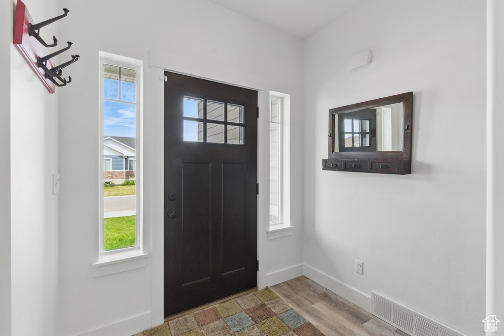 Foyer entrance with visible vents, baseboards, and wood finished floors