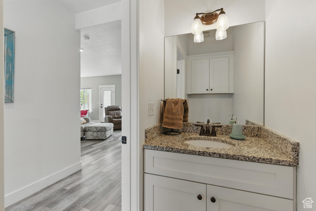Bathroom featuring vanity, baseboards, and wood finished floors