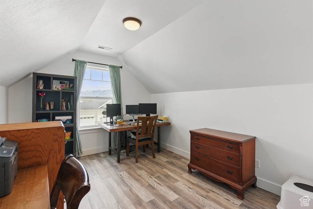 Office featuring visible vents, lofted ceiling, and wood finished floors
