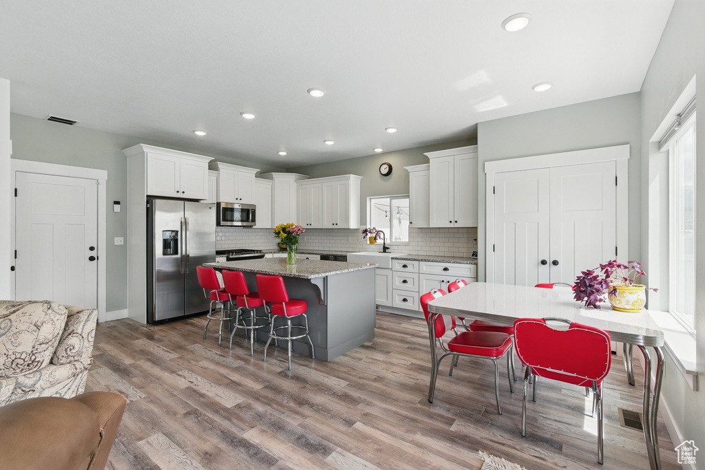 Kitchen featuring appliances with stainless steel finishes, a breakfast bar area, light wood-type flooring, a kitchen island, and visible vents