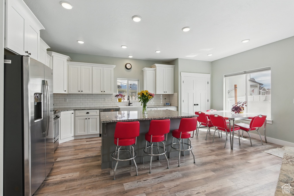 Kitchen featuring appliances with stainless steel finishes, a kitchen island, dark stone countertops, and white cabinetry