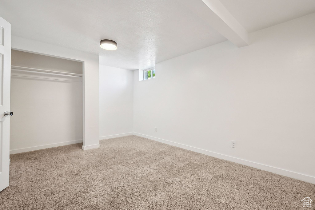 Below grade area featuring baseboards and light colored carpet