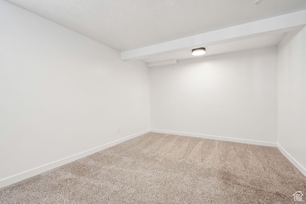 Empty room featuring baseboards and light carpet