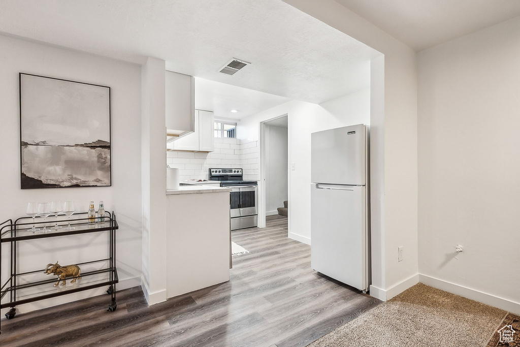 Kitchen featuring visible vents, freestanding refrigerator, light countertops, white cabinets, and stainless steel electric stove