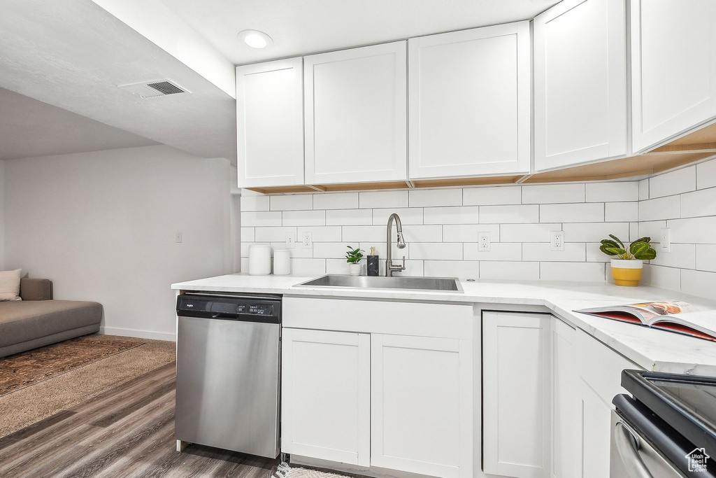 Kitchen featuring wood finished floors, stove, white cabinetry, a sink, and dishwasher