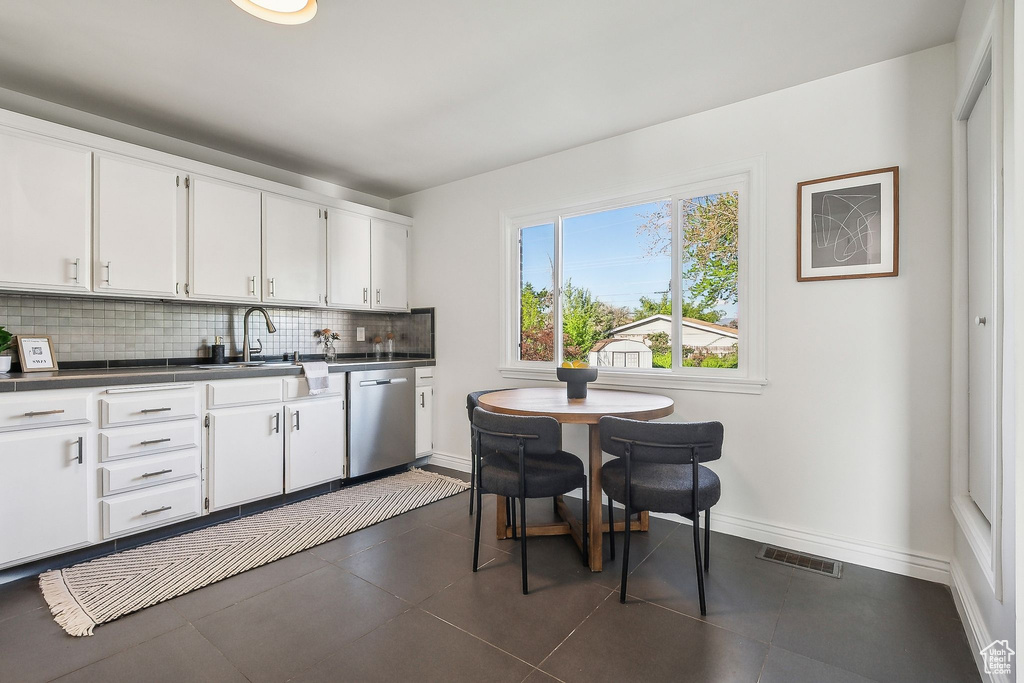 Kitchen featuring dark countertops, a sink, dishwasher, backsplash, and visible vents