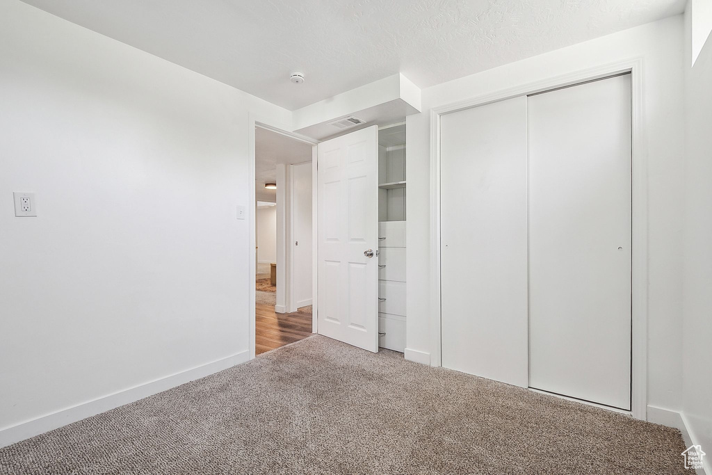 Unfurnished bedroom featuring carpet floors, baseboards, visible vents, and a closet