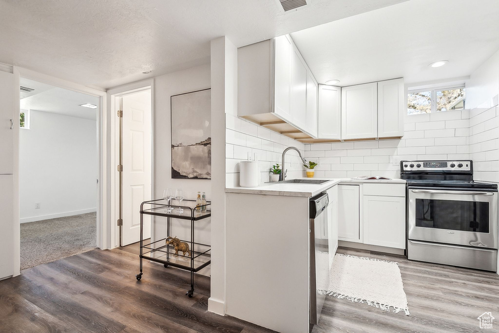Kitchen featuring a sink, light countertops, stainless steel appliances, and wood finished floors