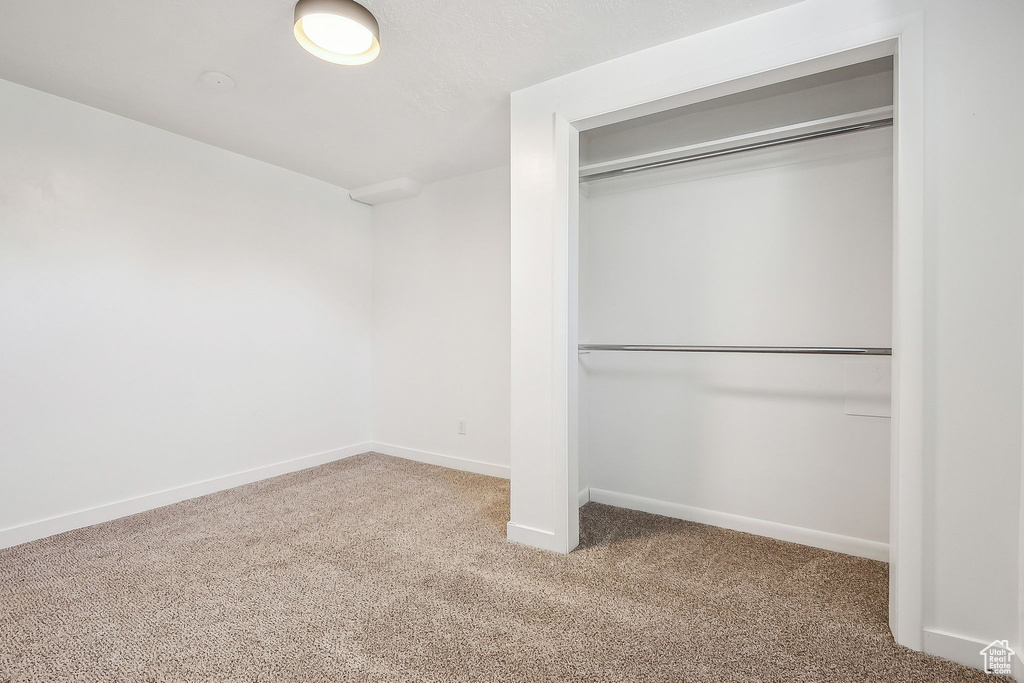 Unfurnished bedroom featuring baseboards, carpet, and a closet