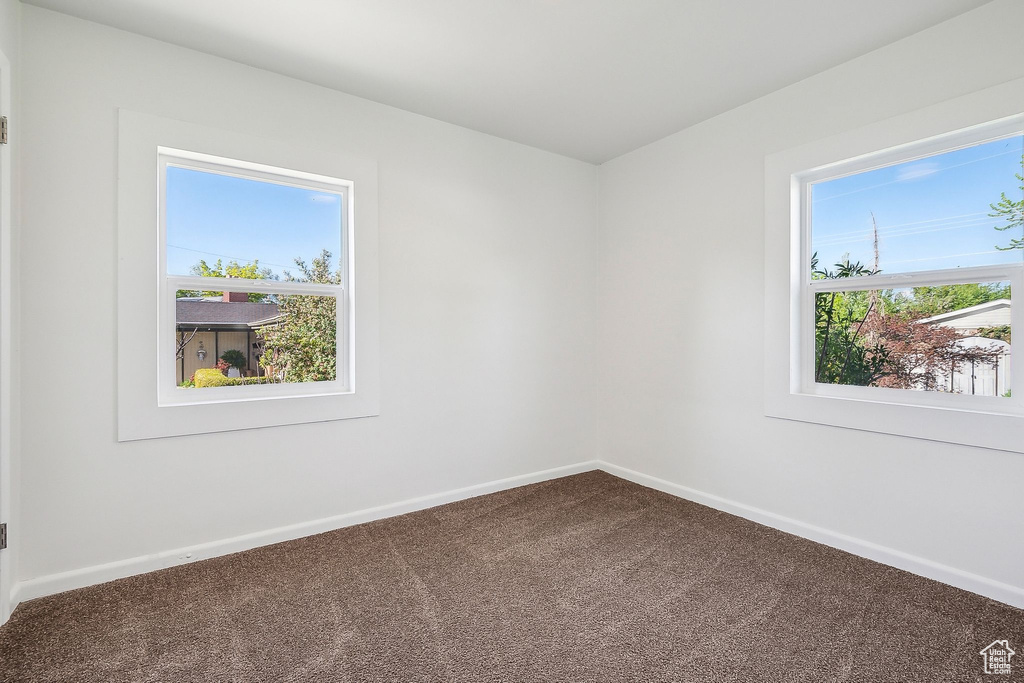 Empty room featuring dark colored carpet and baseboards