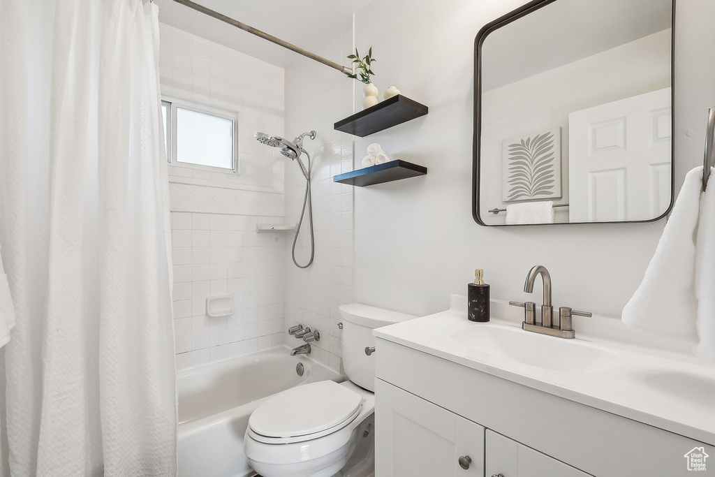 Bathroom with toilet, shower / tub combo, and vanity