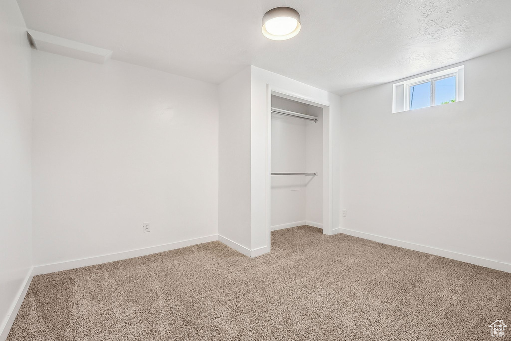 Unfurnished bedroom featuring baseboards, carpet flooring, a textured ceiling, and a closet