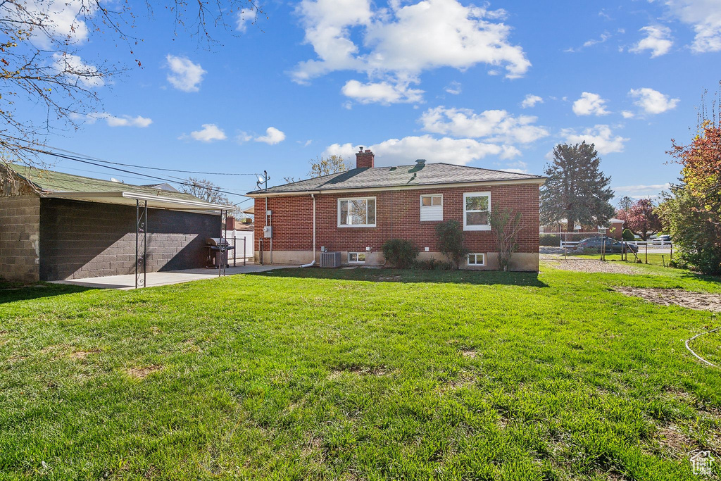 Rear view of house with a lawn, brick siding, fence, and a chimney