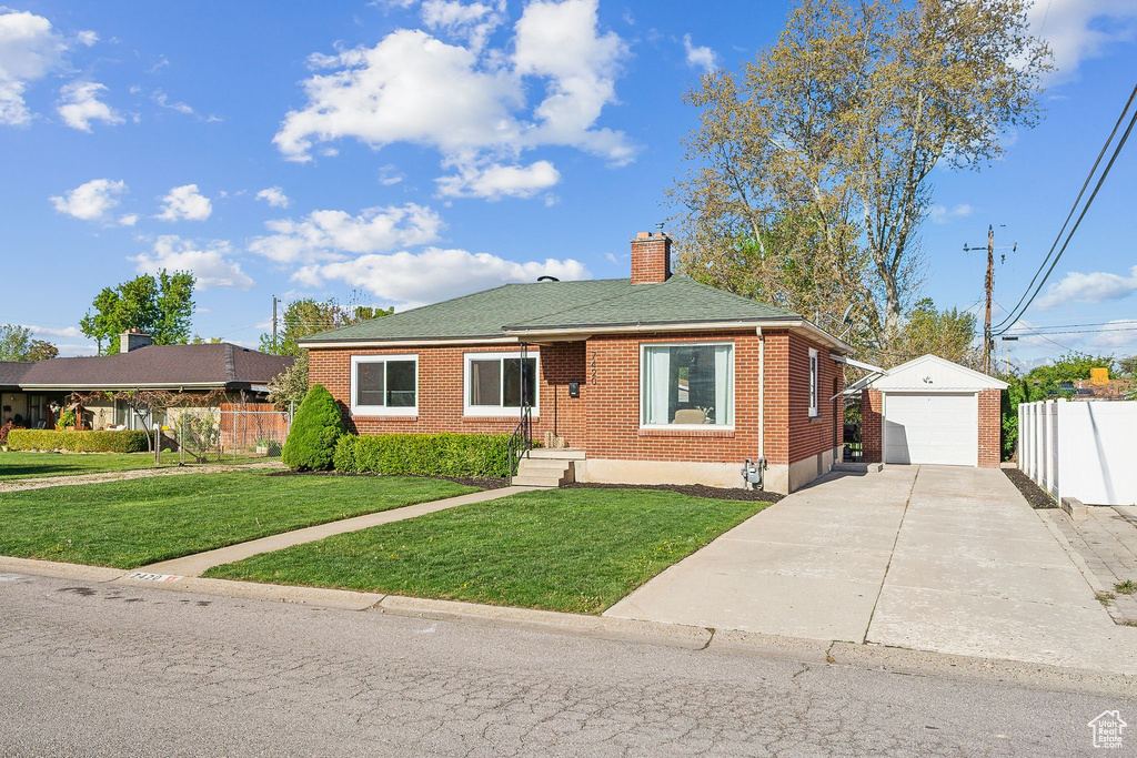 Bungalow featuring fence, brick siding, an outbuilding, a chimney, and driveway