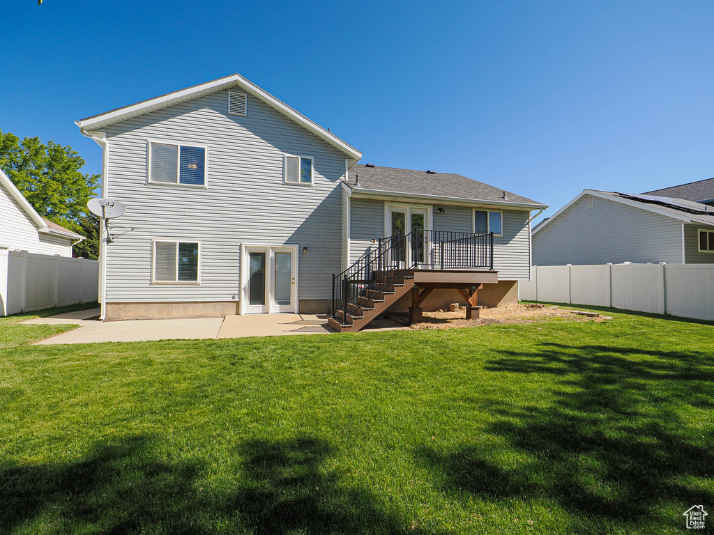 Rear view of property featuring a wooden deck, a fenced backyard, a patio area, a yard, and stairway