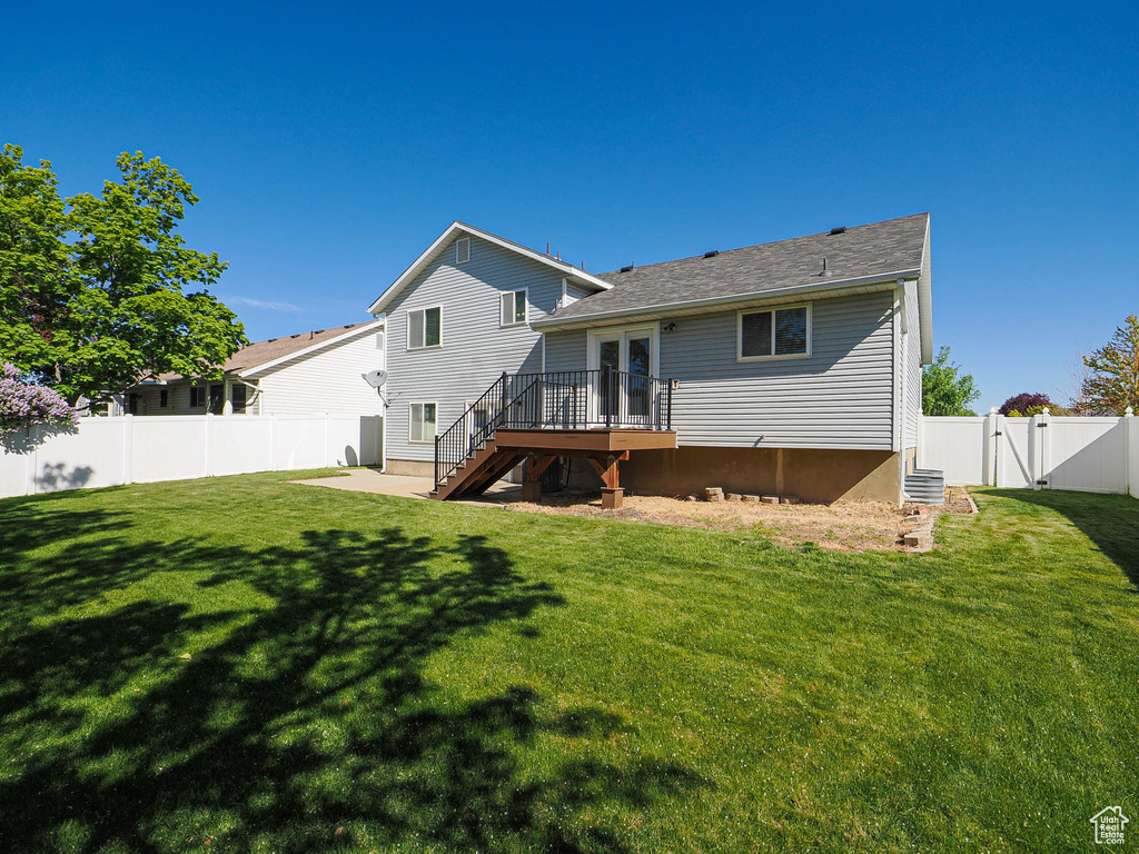 Rear view of house featuring a wooden deck, a gate, stairway, a fenced backyard, and a yard