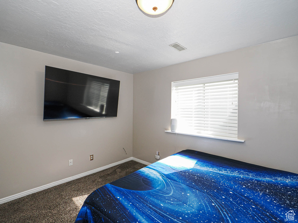 Carpeted bedroom featuring baseboards, a textured ceiling, and visible vents