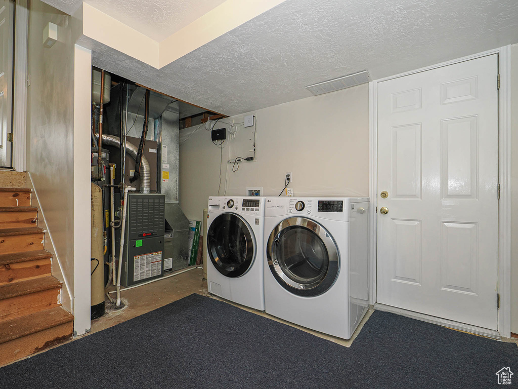 Laundry room featuring washer and dryer, a textured ceiling, laundry area, and heating unit