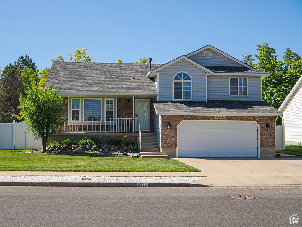 View of front of home featuring a garage, a front lawn, fence, concrete driveway, and a porch