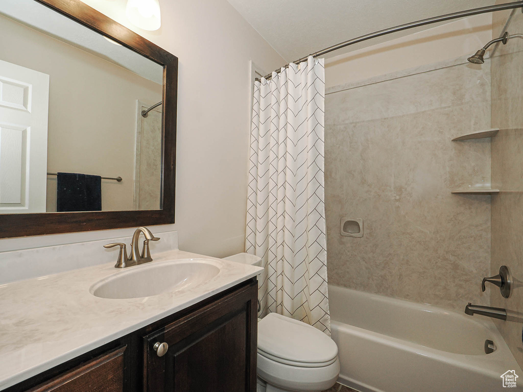 Bathroom with toilet, shower / tub combo, and vanity