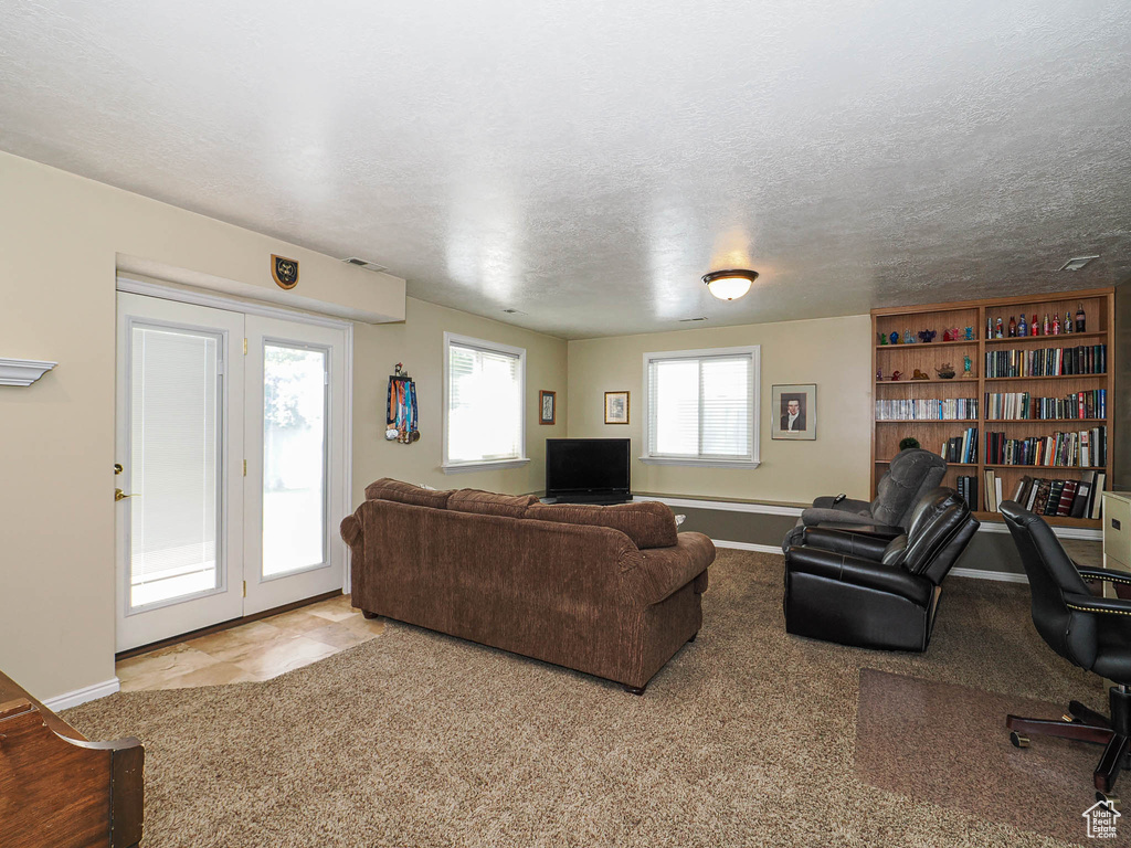 Living area featuring baseboards, a textured ceiling, and visible vents