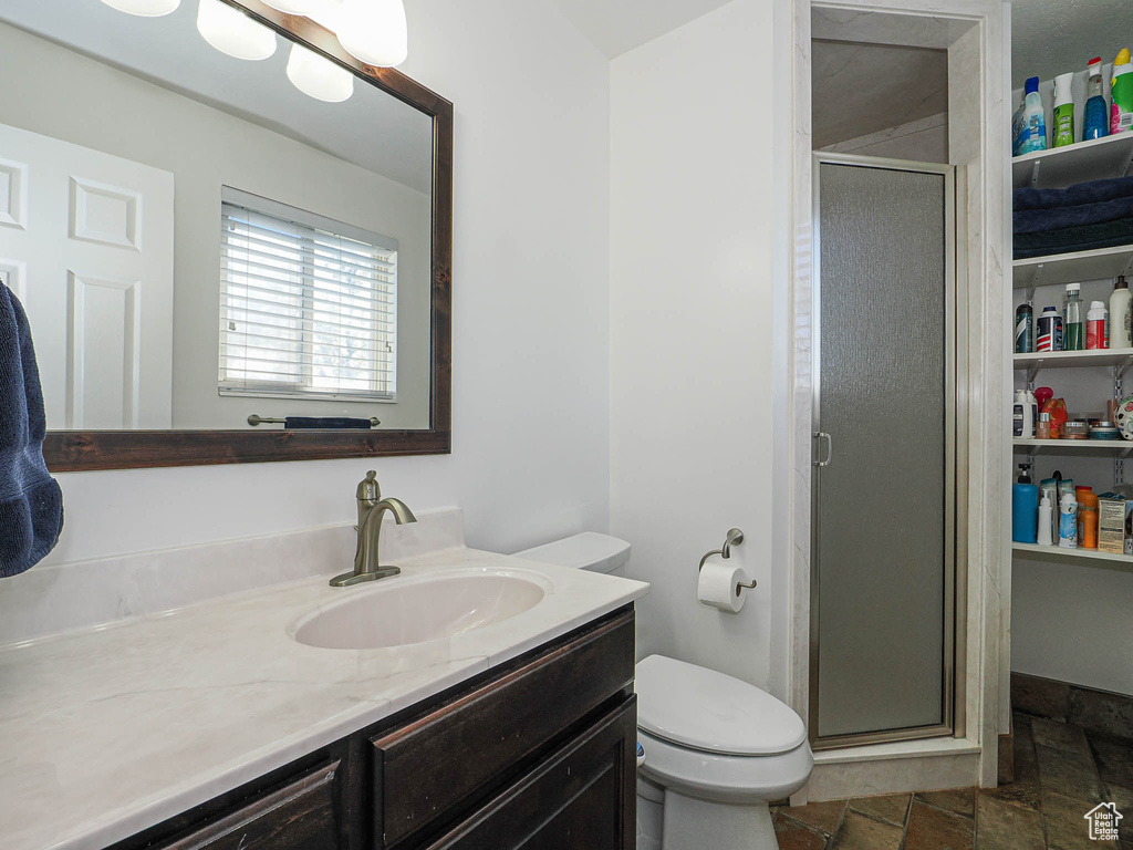 Full bath with vanity, a stall shower, toilet, and stone tile flooring