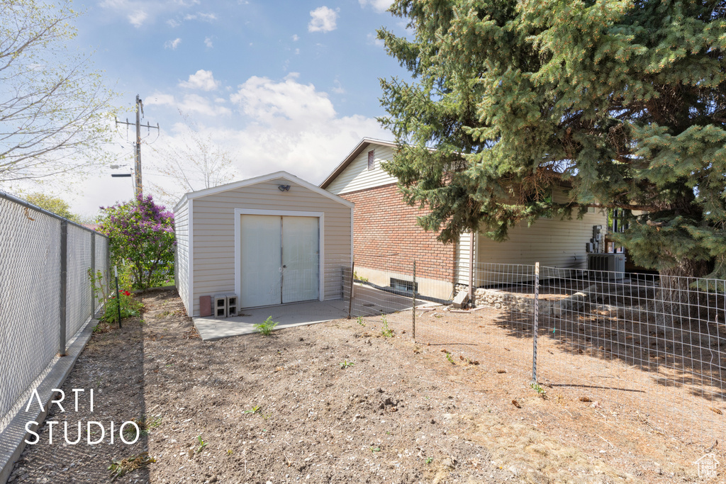 Exterior space with a fenced backyard, an outbuilding, a shed, and brick siding