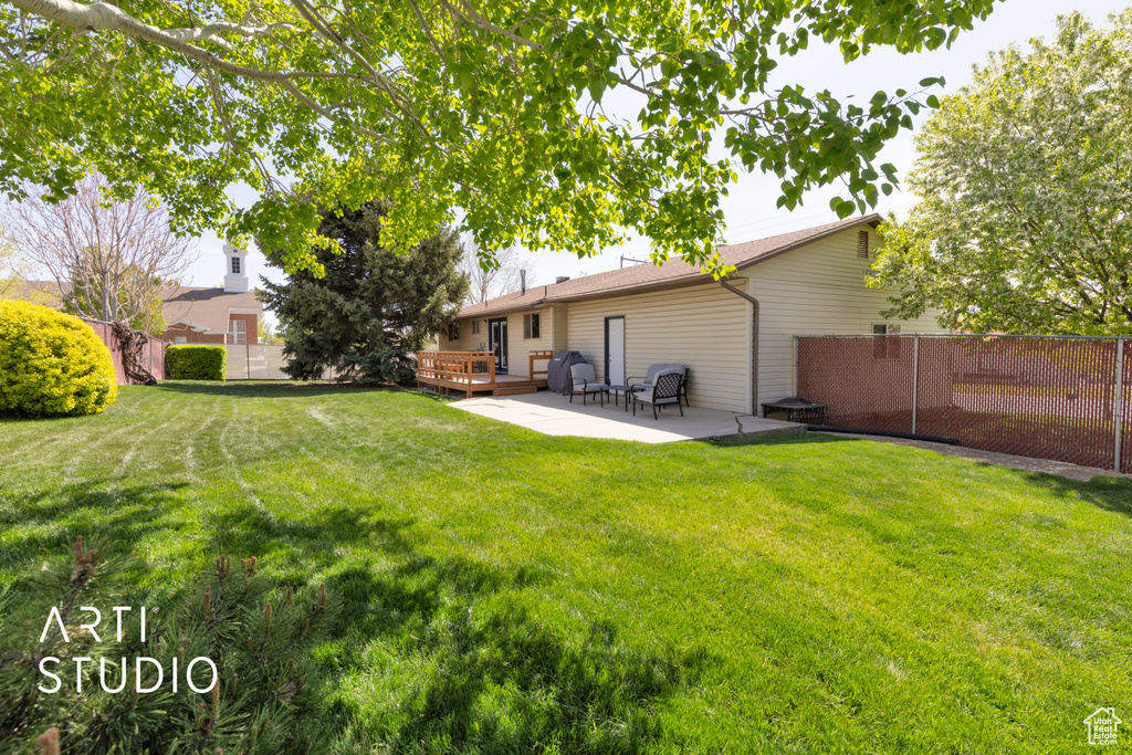 Back of property featuring a yard, a deck, fence, and a patio