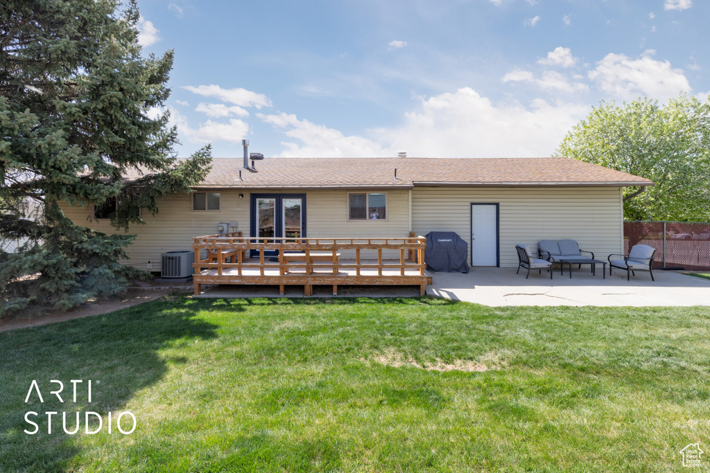 Back of property featuring a lawn, a deck, french doors, and a patio area