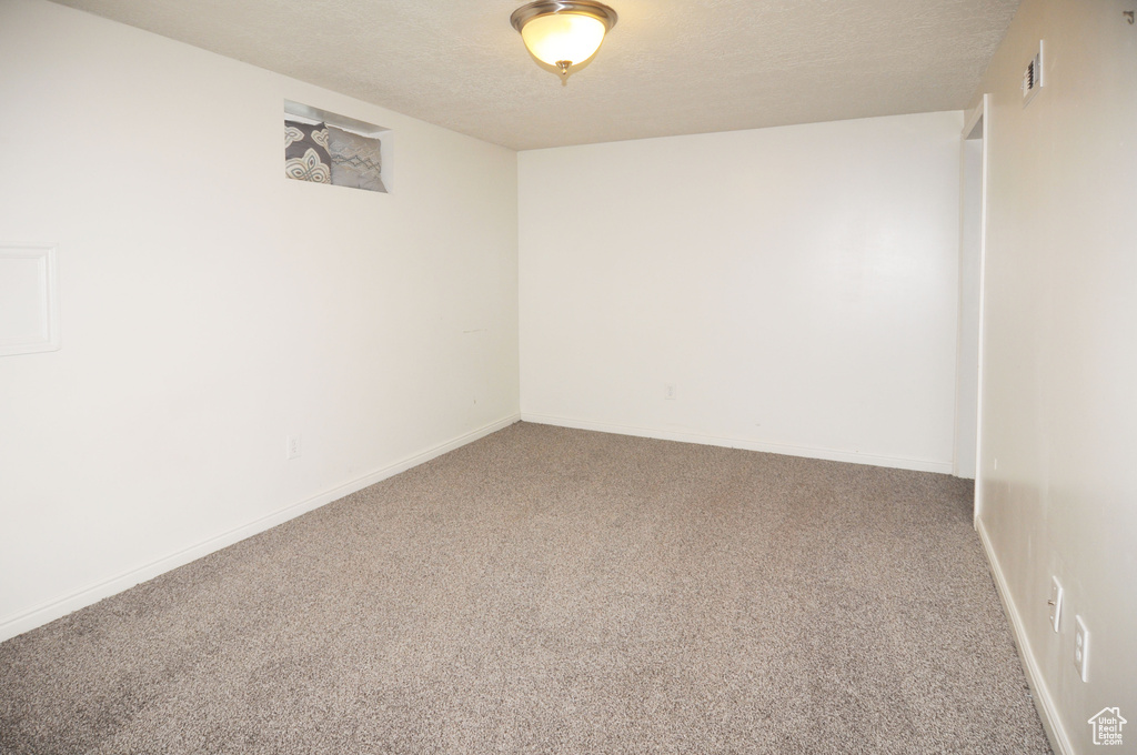 Spare room with a textured ceiling, visible vents, carpet flooring, and baseboards