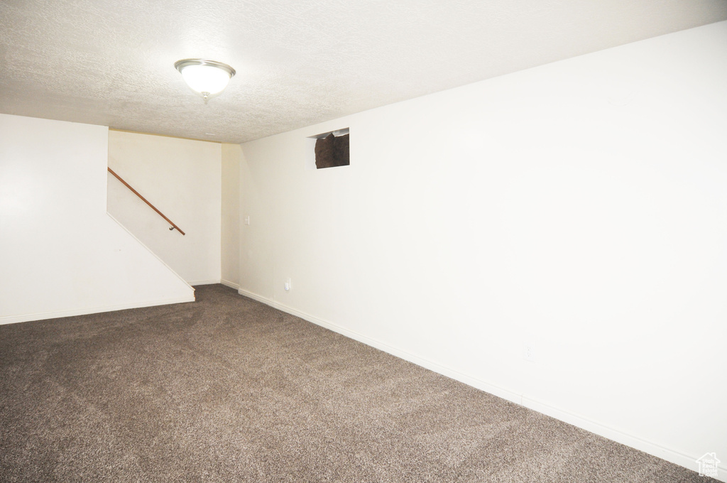 Finished basement featuring a textured ceiling, stairway, carpet floors, and baseboards