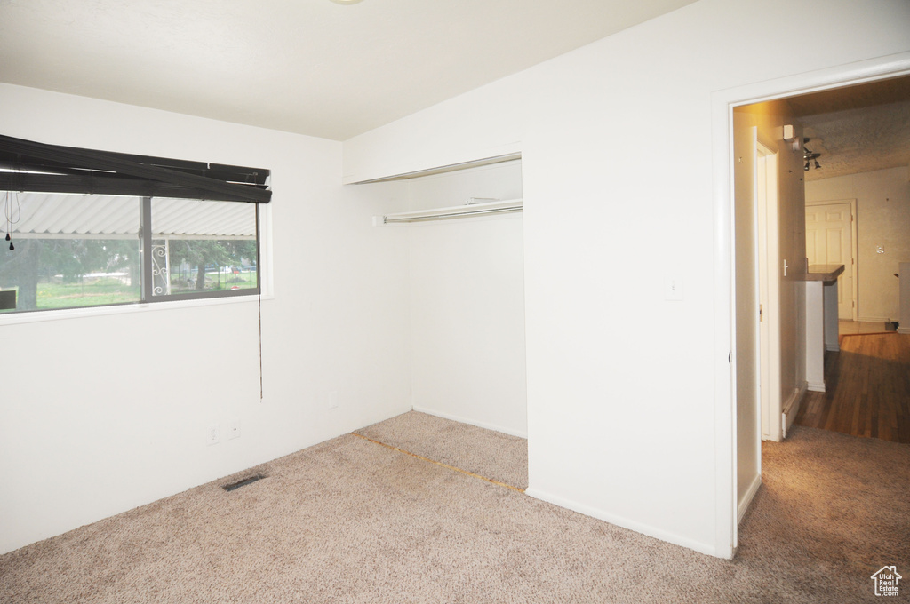 Unfurnished bedroom with a closet, visible vents, and carpet floors