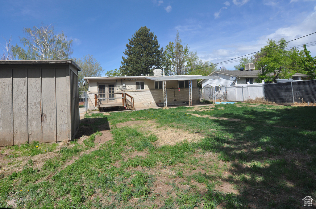 View of yard featuring fence, a storage unit, a wooden deck, and an outdoor structure