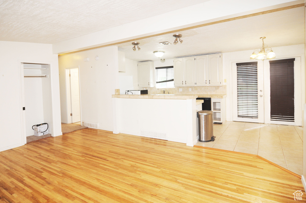 Unfurnished living room with light wood finished floors and a notable chandelier