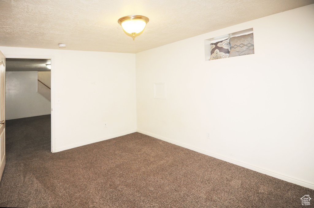 Basement featuring carpet, a textured ceiling, and baseboards