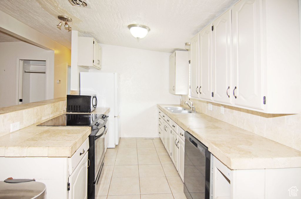 Kitchen with electric stove, a sink, backsplash, light countertops, and dishwasher