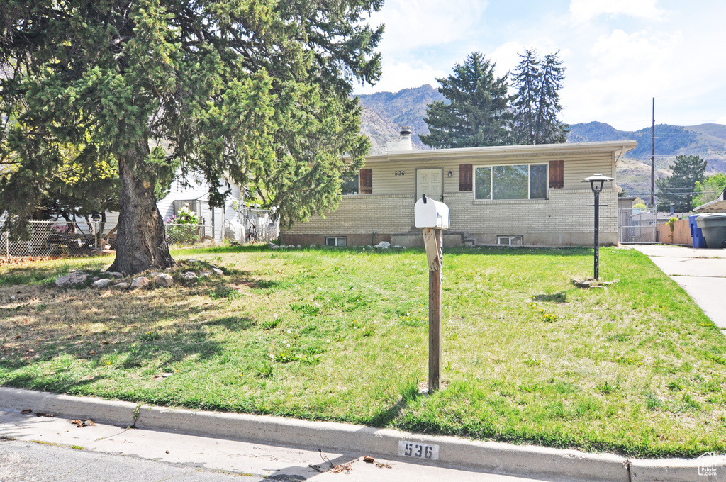 View of front of property featuring fence, a mountain view, and brick siding