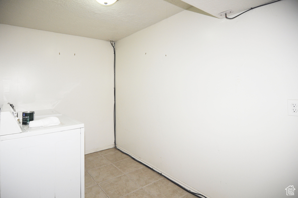 Washroom featuring washer / clothes dryer, light tile patterned flooring, and laundry area