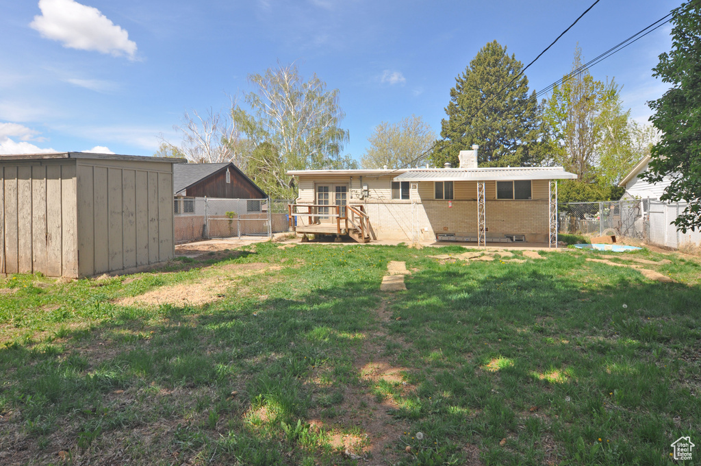 Back of house with a lawn, a storage unit, a chimney, and a fenced backyard