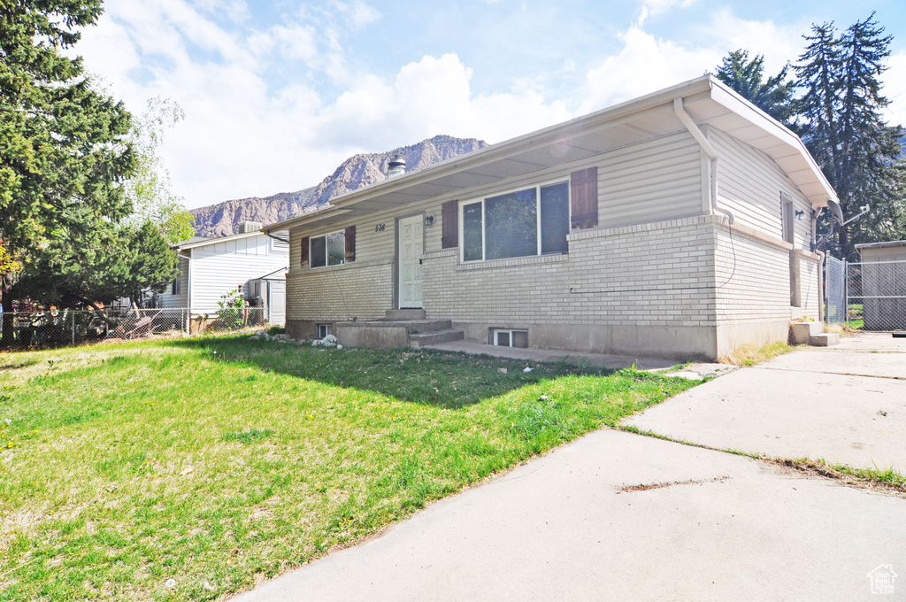 View of front of property featuring a mountain view, fence, a front yard, and brick siding