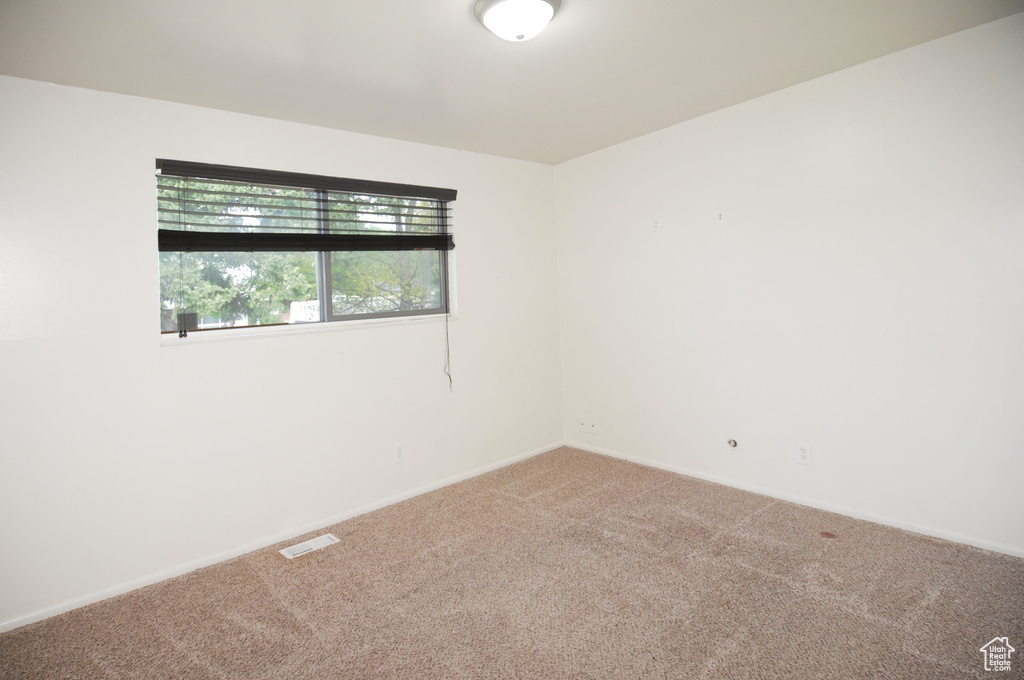 Spare room featuring visible vents, carpet floors, and baseboards