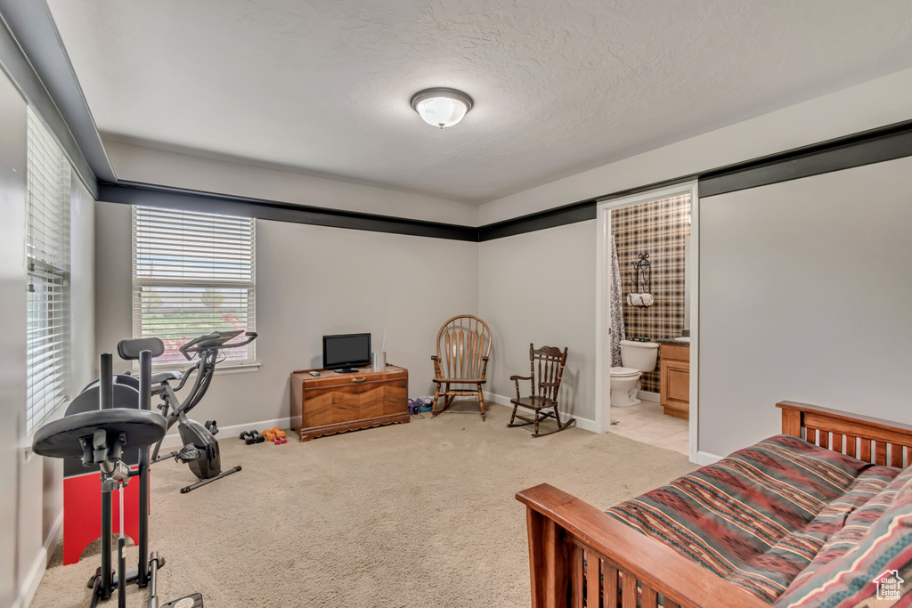 Bedroom with baseboards, ensuite bathroom, and light carpet