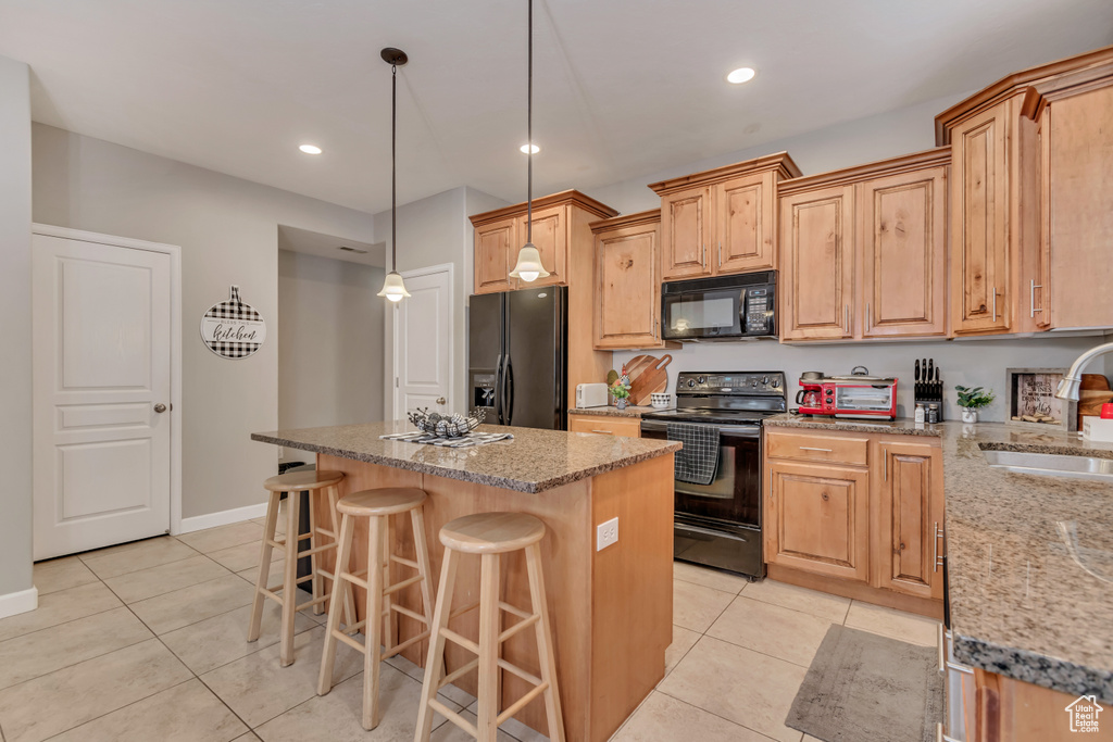 Kitchen with a center island, a sink, light tile patterned floors, and black appliances