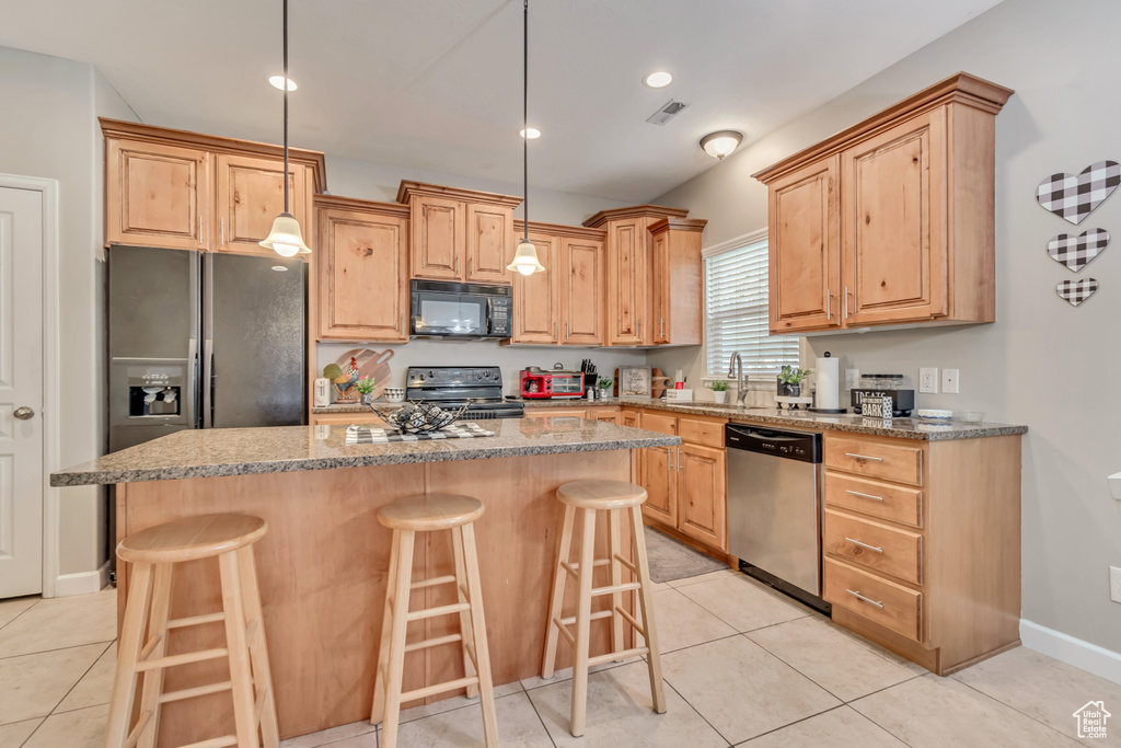 Kitchen with a kitchen bar, visible vents, a center island, a sink, and black appliances