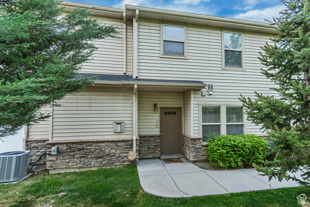 Townhome / multi-family property with central AC unit and stone siding